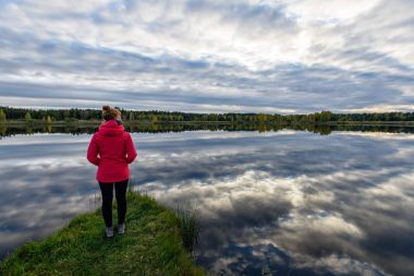 genç kadın doğa toprak yol üzerinde kırmızı ceketli. Letonya
