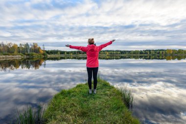 genç kadın doğa toprak yol üzerinde kırmızı ceketli. Letonya