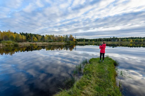 Jonge vrouw in een rood jasje genieten van de natuur op onverharde weg. Letland — Stockfoto