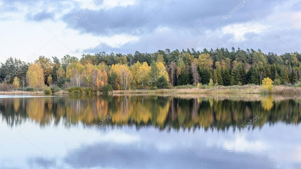 autumn colored trees on the shore of lake with reflections in wa
