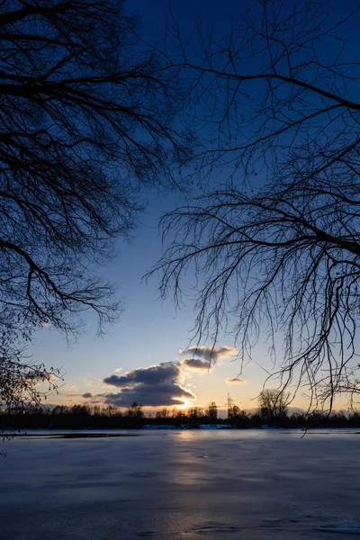 Pôr do sol de inverno colorido com raios de luz que vêm através das árvores — Fotografia de Stock