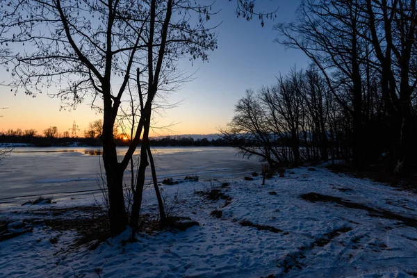 Pôr do sol de inverno colorido com raios de luz que vêm através das árvores — Fotografia de Stock