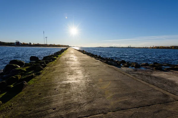 Les gens profitant du coucher de soleil sur le brise-lames dans la mer avec lumière — Photo