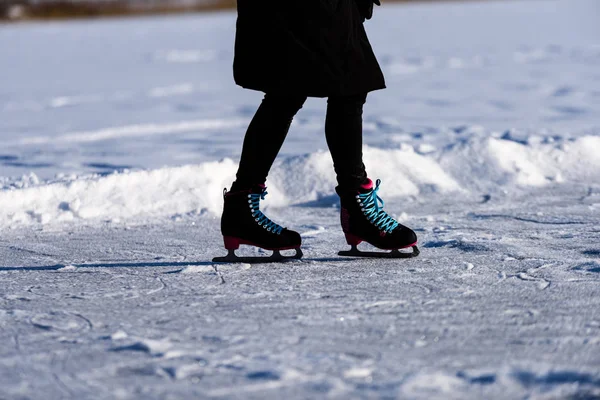 Young woman in black coat skating on the frozen lake in snow — Stock Photo, Image