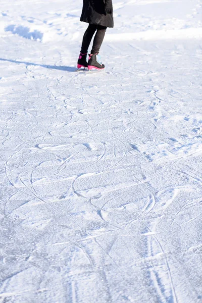 穿黑大衣的年轻女子在冰雪冰冻的湖面上滑冰, le — 图库照片