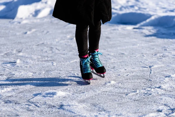 Fiatal nő fekete kabátot, korcsolyázás a befagyott tavon a hóban — Stock Fotó