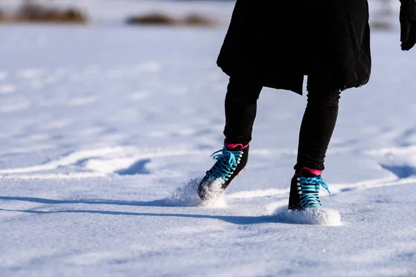 Giovane donna in cappotto nero pattinare sul lago ghiacciato nella neve — Foto Stock