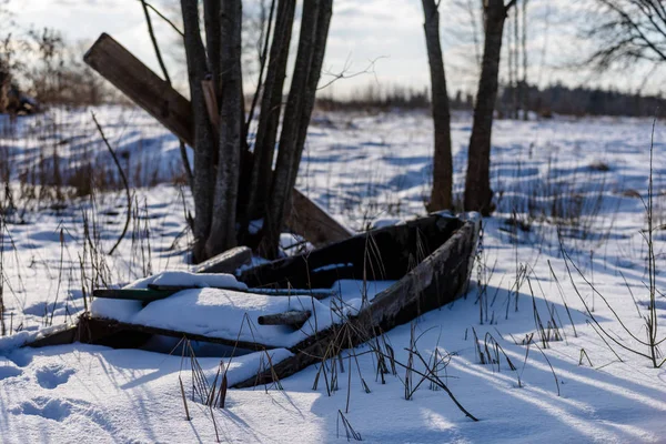 Cena rural de inverno com neve e troncos de árvore no frio. Velho barco — Fotografia de Stock