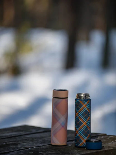 Thermoses colorées sur table en bois dans la forêt d'hiver — Photo