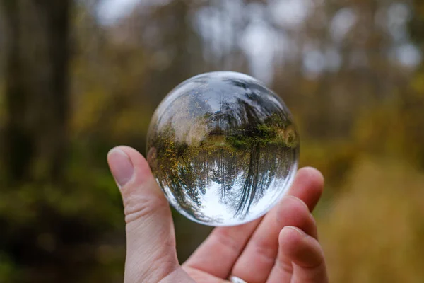 Mężczyzna ręka trzymając kryształową szklaną kulę na tle natury w — Zdjęcie stockowe