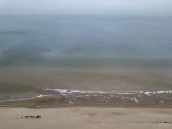 Praia à beira-mar com água coberta de neblina — Fotografia de Stock