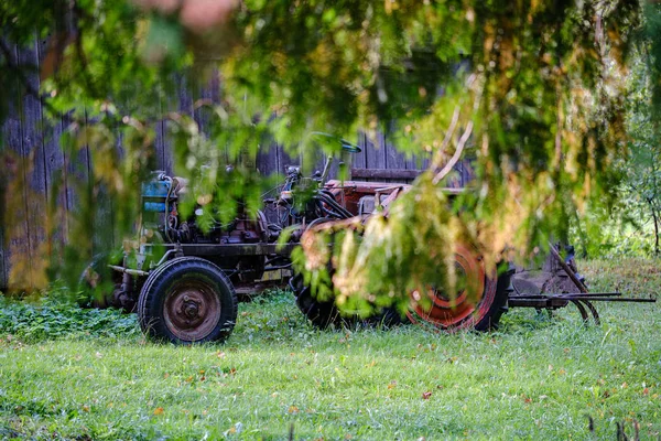 รถแทรกเตอร์เก่าถูกทิ้งร้างในป่าทุ่งหญ้าสีเขียว — ภาพถ่ายสต็อก
