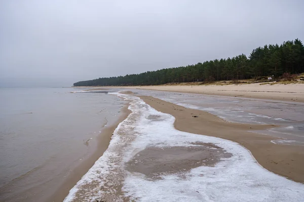 Gefrorener Meeresstrand mit Sand und erstem Schnee an bewölkten Tagen — Stockfoto