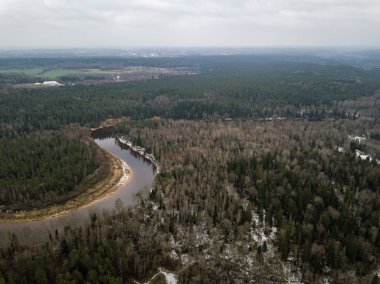 Kış ormanındaki nehirde yukarıdan yeşil ağaçlar var. Letonya 'daki Gauja nehrinin hava aracı görüntüsü.