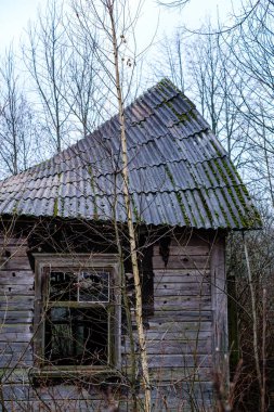 Sonbaharda kırık mobilyaları ve boş pencereleri olan terk edilmiş eski bir ev.