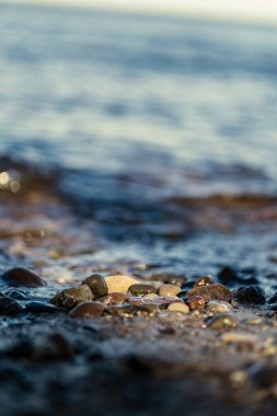 Güneşli bir günde kumsalda kayalara vuran dalgalar mavi gökyüzü ve kum dokusunda berrak su. çakıl