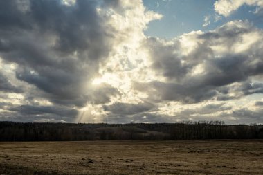 Dramatik bulutlar ve güneş ışınlarıyla gölün üzerinde gün batımı