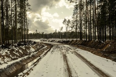 Kışın karlı ve çamurlu ormanda yeni bir yol inşaatı