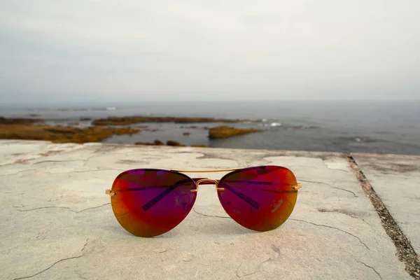 Sonnenbrille auf einer Steinbrüstung am Meeresufer — Stockfoto