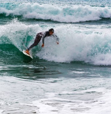 Oyambre, İspanya - 6 Temmuz 2016: Bilinmeyen sörfçü dalgaları arasında