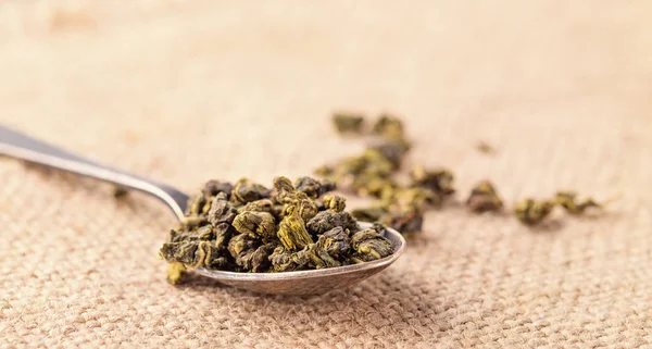 Dry leaves of green tea and teaspoon