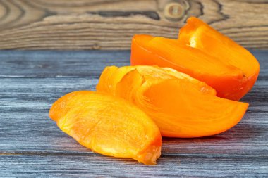 Olgun bir turuncu Trabzon hurması ahşap bir masa üzerinde parçalarını