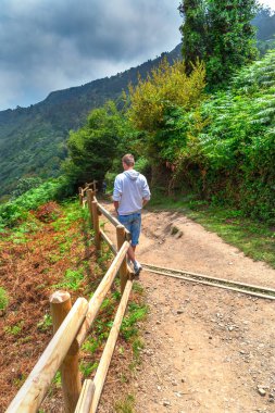 Dağlarda bir toprak yolda genç adam iner