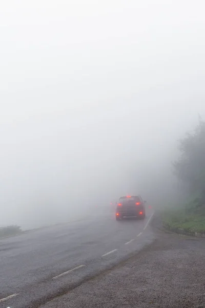 The car on the road in dense fog, a shot following