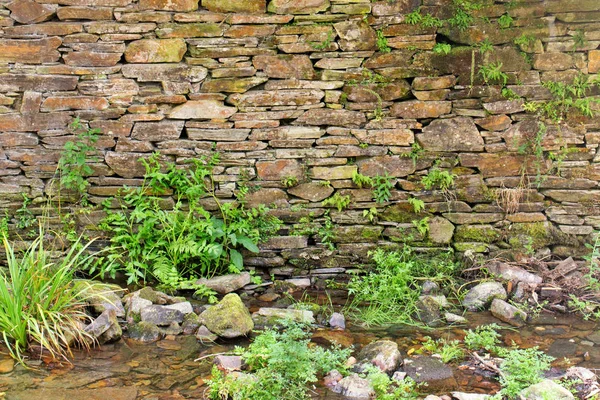 Oude stenen muur bij een stream — Stockfoto