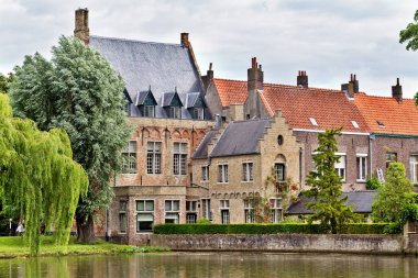 Bruges, Belçika aşkın göl kıyısında antik ev. Tuğla ev kiremit çatılı, yakın büyük bir yeşil söğüt
