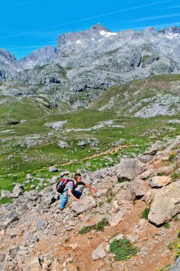Fuente De, İspanya - 10 Temmuz 2016: Dağlarda bir sırt çantası ile genç adamın bir yamaçta alır. Güneşli yaz gün, mavi gökyüzü