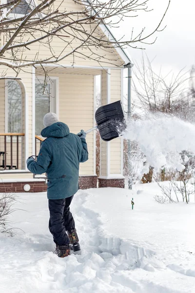 Een man verwijdert sneeuw in de buurt van een landhuis, worden gewist van het pad — Stockfoto