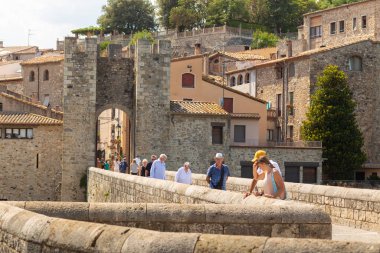 Besalu, İspanya - 2 Ağustos 2019: Besalu girişinin önündeki taş köprüde turistler.