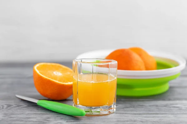 半杯橙汁和新鲜榨橙汁放在木制桌子上的杯子里 — 图库照片