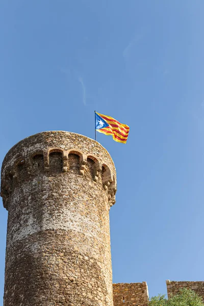 Antiga torre de pedra iwith bandeira da Catalunha n a fortaleza contra o céu azul . — Fotografia de Stock
