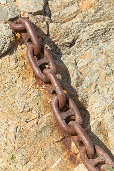 Řetězec se rzí na žlutém přírodním kameni. — Stock fotografie
