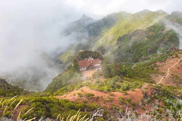 Uma casa branca com um telhado de azulejos nas montanhas entre as nuvens . — Fotografia de Stock