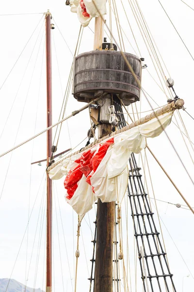 Tackles staré plachetnice - stěžeň, stěžeň, zvednuté červenobílé plachty, lana. — Stock fotografie