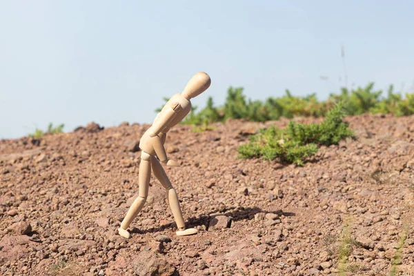 Wooden man hardly walks on the ground without plants in the mountains.