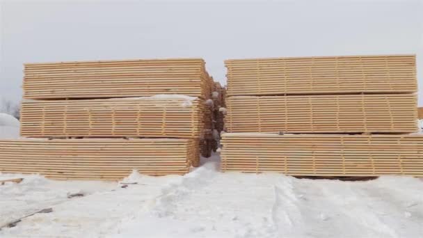 Доски в стопках хранятся на открытом воздухе зимой. Лесопилка . — стоковое видео
