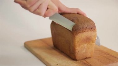 Bir kadın bir somun ekmeği bıçakla keser. 50 peni.