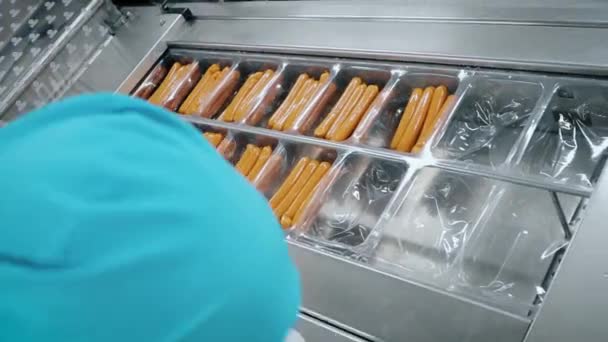 Fleischproduktion. Der Arbeiter packt Würstchen ein. — Stockvideo