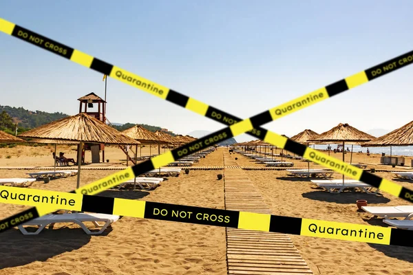 Barrier tape - quarantine, isolation, entry ban. Do not cross. almost empty beach summer sea view