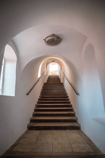 Stare schody uliczne w tunelu prowadzą w górę. Są kamienne schody. Ściany tunelu są białe z poręczą. — Zdjęcie stockowe