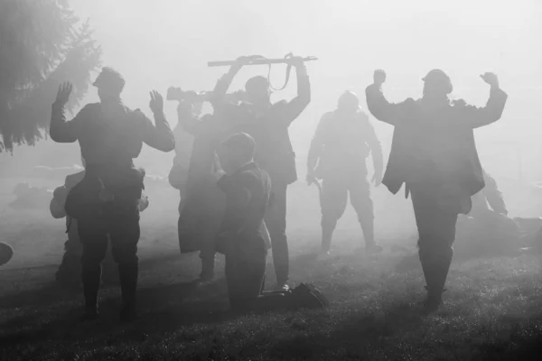 Siluety vojáků v uniformách během války s puškami na bojišti. Celá oblast je v kouři a sluneční paprsky vykukují skrz. Na fotce jsou rukojmí.. — Stock fotografie