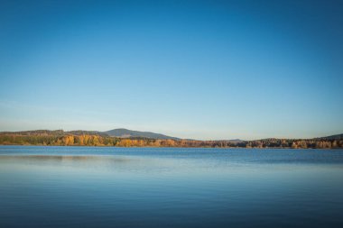 Lipno Barajı - Cerna ve Posumavi, Çek Cumhuriyeti, aydınlık bir yaz gününde. Göl sakin, temiz mavi suyu var. Gökyüzünde hiç bulut yok..