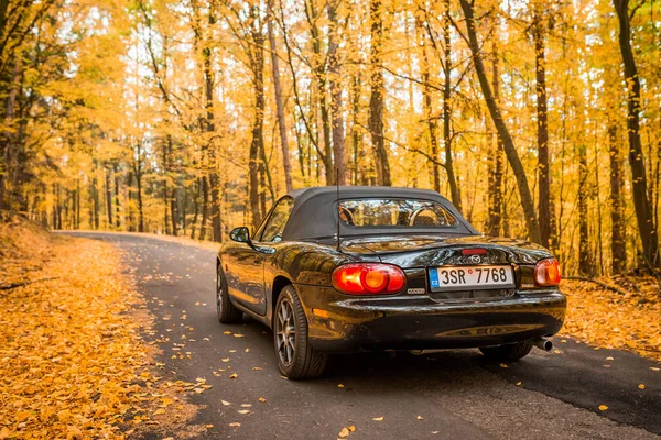 PRAGUE, REPÚBLICA CHECA, OUTUBRO 2019: Mazda MX-5 Miata NB segunda geração, ano modelo 1999 Em uma estrada forrest no outono com belas árvores de queda coloridas no fundo — Fotografia de Stock