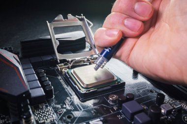 Soketteki ana işlemcinin üstündeki termal macun bileşiği nin tekniker sıkma veya uygulama yakın. Bilgisayar donanımını onarma veya yükseltme kavramı.