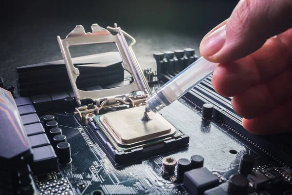 Cerca de técnico exprimir o aplicar el compuesto de pasta térmica en la parte superior de la CPU principal en el zócalo. Concepto de reparación o actualización de hardware informático . — Foto de Stock