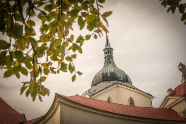 Zdar nad Sazavou 'daki Zelena hora' daki Nepomuk Kilisesi 'nin hac kilisesi, ulusal kültür mirası ve Unesco Dünya mirası anıtı - ön planda sonbahar yapraklarıyla yakın çekim.